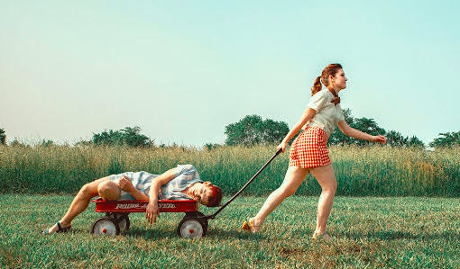 A girl carrying boy on the radio flyer wagon stroller