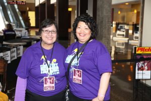 two women in purple T shirts are smiling